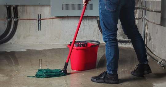 Woman mopping flood from water leaks in basement