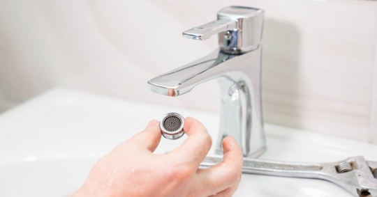 repairman removes and cleans the aerator from water stone and rust