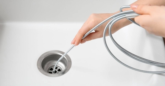 Woman Cleaning Drain with Plumber's Snake, Closeup