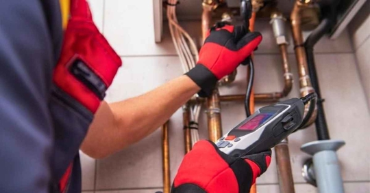 Technician uses gas detecting device to check heating system