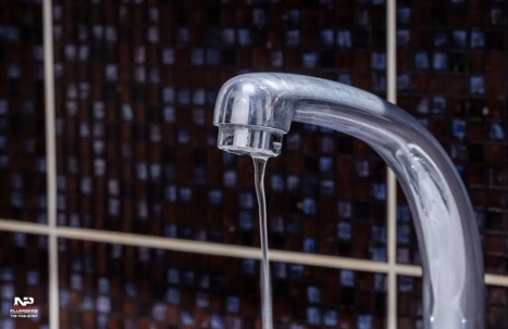 A leaky faucet with a dark tile background.