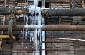 Icy pipes on a brick building exterior.