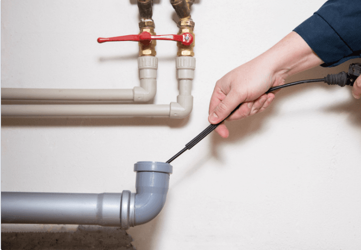 A plumber inserts a camera snake into a drain pipe.